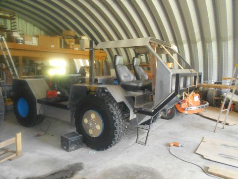 1992 Ford Bronco - A custom-built all-terrain vehicle with oversized tires sits in a workshop, appearing unfinished.