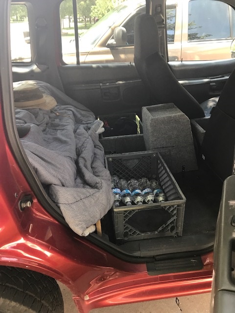 2000 Ford Explorer - The interior of a red SUV is shown, containing a crate filled with water bottles and a blanket.