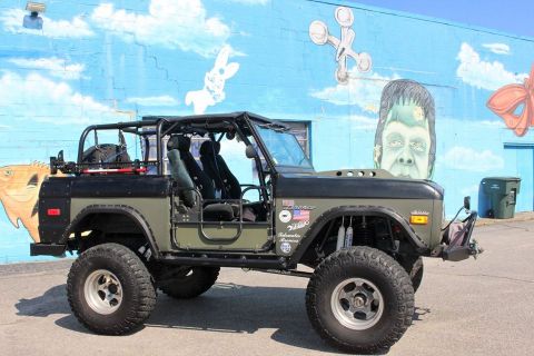 1972 Ford Bronco - This modified Ford Bronco, with its distinctive roll cage and off-road tires, is parked against a vibrant mural.