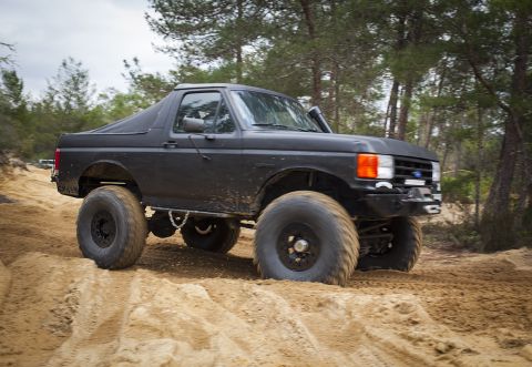 1989 Ford Bronco - This modified Ford Bronco navigates a sandy terrain, its off-road capabilities.