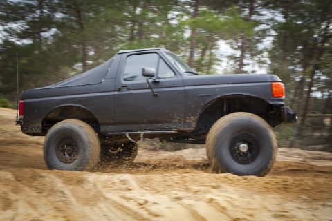 1989 Ford Bronco - This lifted Ford Bronco navigates a sandy terrain, its off-road capabilities.