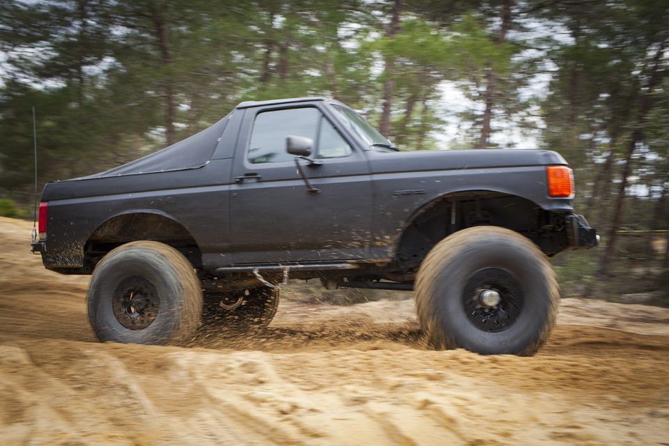 Dark gray 1987 Ford Bronco off-roading with large tires