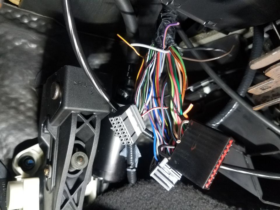 Wiring harness with multiple colorful wires and gray and black connectors visible under a vehicle's dashboard