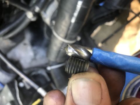 1974 Ford Bronco - A close-up shot shows a person holding a threaded bolt and a drill bit with blue tape wrapped around its shaft. The background appears to b…