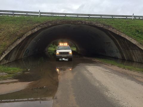 1993 Ford Bronco - A white Ford Bronco with four yellow emergency lights on its roof drives through a flooded underpass. The vehicle is partially submerged in…