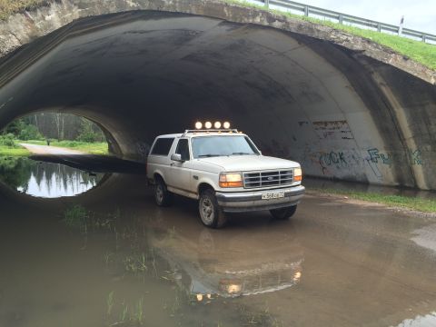 1993 Ford Bronco - A white 1993 Ford Bronco is parked in a flooded underpass. The vehicle has four auxiliary lights mounted on the roof.