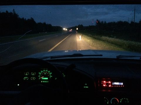 1993 Ford Bronco - View from inside a vehicle at night, looking out the windshield at a highway. The dashboard gauges and a car stereo are illuminated.