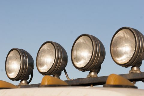 1993 Ford Bronco - A row of four large, round, aftermarket auxiliary lights are mounted on a dark metal bar above the windshield of a white vehicle. The light…