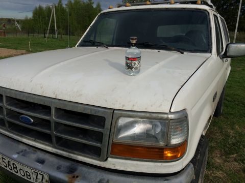 1993 Ford Bronco - A white Ford Bronco is parked outdoors on a grassy area. A bottle of Espolon tequila rests on the hood of the vehicle.