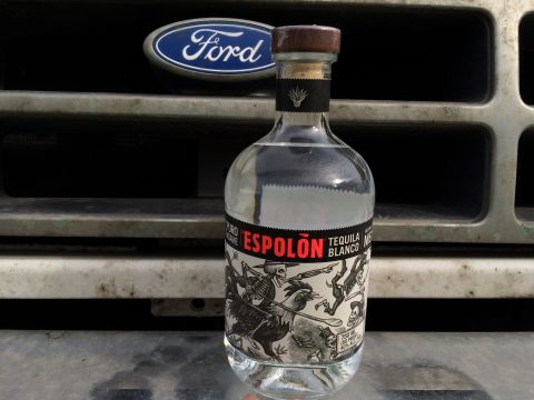 1993 Ford Bronco - A bottle of Espolón Tequila Blanco sits in front of the grille of a classic Ford vehicle, possibly a 1993 Ford Bronco, with its emblem visi…