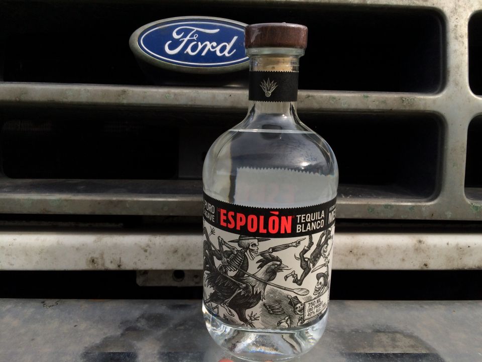 Bottle of Espolon Tequila Blanco in front of a Ford Bronco grille.