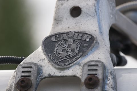 1993 Ford Bronco - A close-up shows a metallic emblem on a vehicle part that reads "CARR KING OF THE MOUNTAIN". The emblem is oval-shaped with a checkered shi…