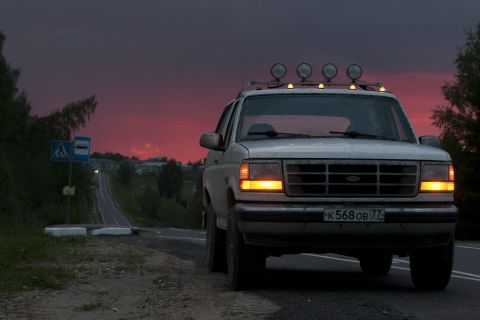 1993 Ford Bronco - A white SUV is seen from the front on a road as the sun sets.