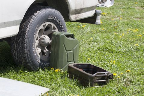 1993 Ford Bronco - A green jerry can and an open oil drain pan sit on the grass next to the rear tire of a white Ford Bronco. The vehicle appears to be parked…