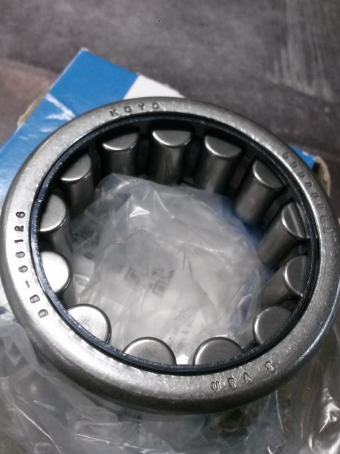 1996 Ford Bronco - A close-up view of a KOYO brand roller bearing with part number DB-60126 visible on the outer race. The bearing is partially wrapped in pla…