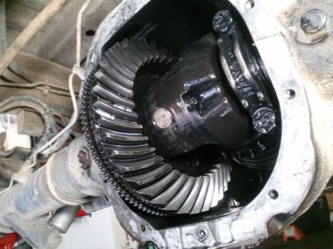 1996 Ford Bronco - A close-up view of the open differential housing of a vehicle, revealing the ring gear and pinion gear assembly. The gears are coated in da…