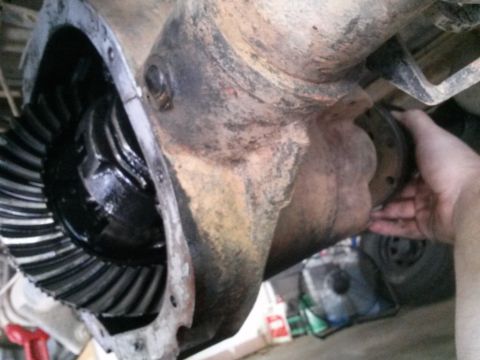1996 Ford Bronco - A close-up view of the differential housing of a vehicle, showing the ring gear and a hand holding a driveshaft flange. The differential is…