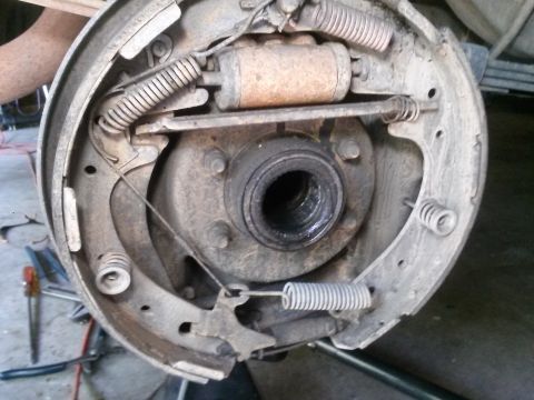 1996 Ford Bronco - A close-up view of the internal components of a drum brake system, showing brake shoes, springs, and the wheel cylinder. Tools and other pa…