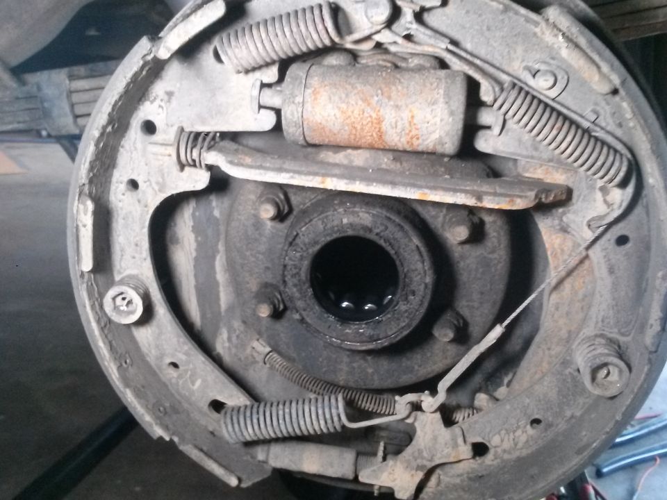 Close-up of a drum brake assembly with brake shoes, springs, and wheel cylinder visible.