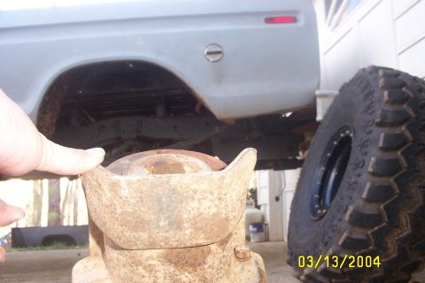 1979 Ford F-150 - A close-up view of a rusty metal component in front of a truck's rear wheel well and a large tire.