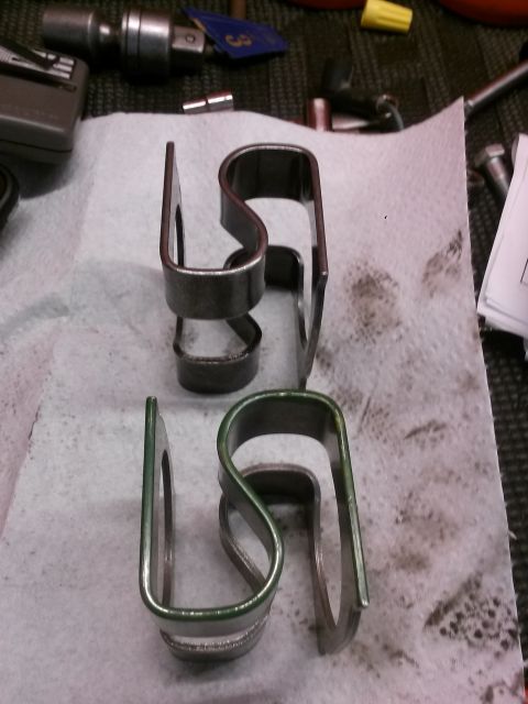 1996 Ford Bronco - Two metal clips, one with a green coating, are laid out on a white paper towel. Various tools and hardware are visible in the background.