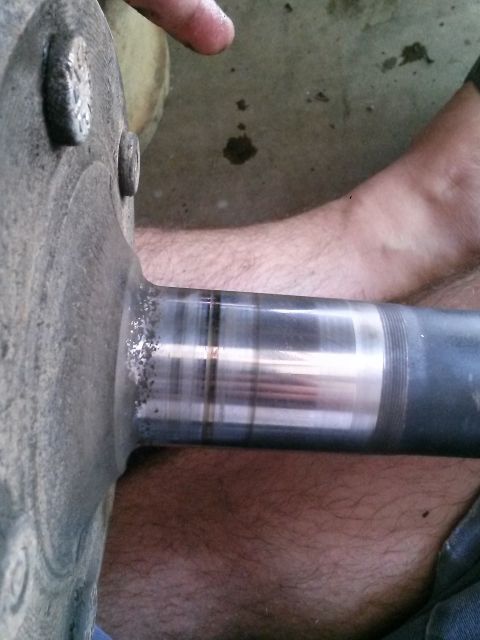 1996 Ford Bronco - A close-up view shows a metal axle shaft with visible wear marks and some debris on the flange. The shaft is connected to a larger, grey, c…