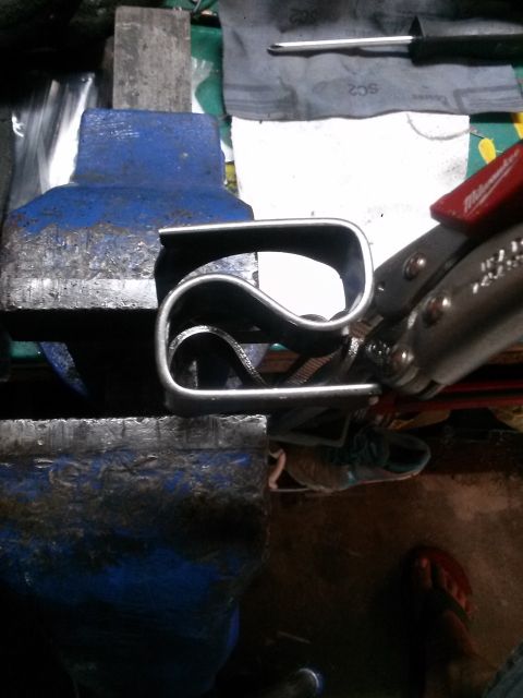 1996 Ford Bronco - A pair of pliers is bending a metal object that is clamped in a vise. Tools and a shoe are visible in the background.