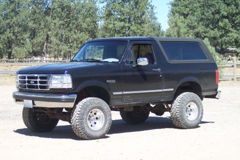 1995 Ford Bronco - A black Ford Bronco with a lifted suspension and off-road tires sits parked outdoors.