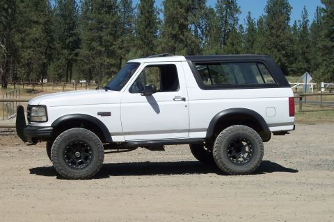 1995 Ford Bronco - This white 1995 Ford Bronco is seen from the side, black trim and aftermarket wheels.