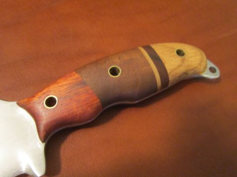 1974 Ford Ranchero - A close-up shot of a knife handle made of different wood sections and brass pins, resting on a brown leather surface.