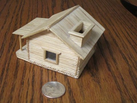 1974 Ford Ranchero - A miniature log cabin model made of toothpicks sits on a wooden table next to a quarter.