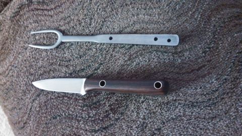 1974 Ford Ranchero - A metal fork with two tines and a knife with a wooden handle are laid out on a textured brown surface.