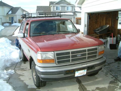 1996 Ford Bronco - Front view of a 1996 Ford Bronco with a roof rack, parked in a snowy driveway next to an open garage.