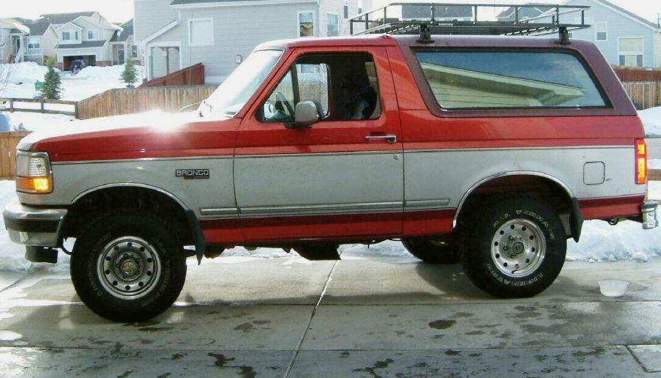 Red and silver Ford Bronco with roof rack, side view