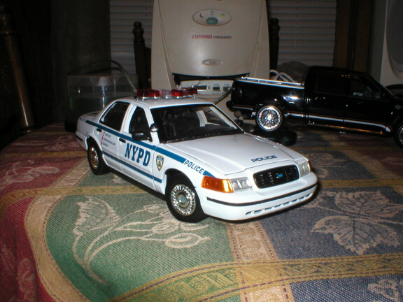 Scale model white NYPD Crown Victoria police car with roof lightbar