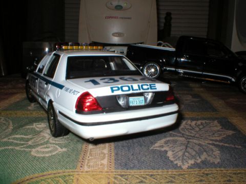1989 Ford Crown Victoria - A model police car is parked indoors next to a model pickup truck.