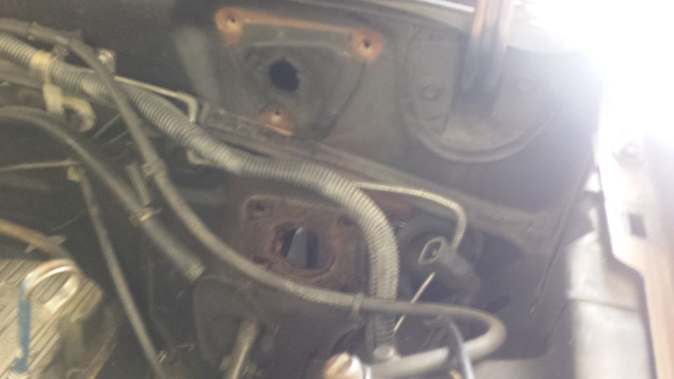 Engine bay with wiring and hoses, some rust visible