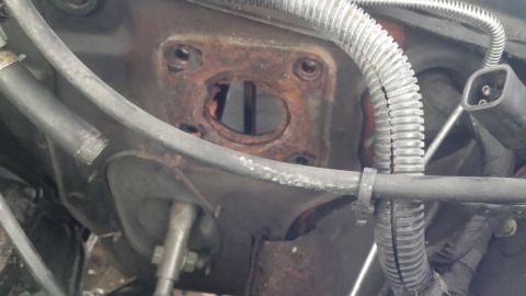 1980 Ford Mustang - Close-up view of a rusted brake booster mounting plate, showing hoses and electrical connectors.