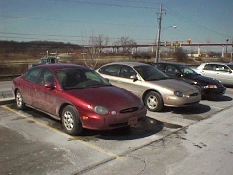 1999 Ford Taurus - Multiple Ford Taurus sedans are parked in a lot under a clear sky.