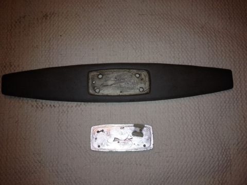 1968 Mercury Cougar - Two automotive parts, likely an emblem and its backing, are laid out on a textured surface.