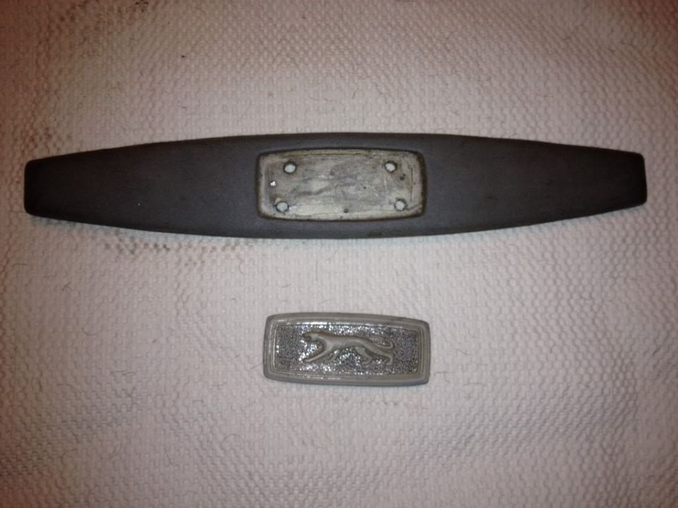 1968 Mercury Cougar emblem with a leaping cat and a black trim piece with mounting holes