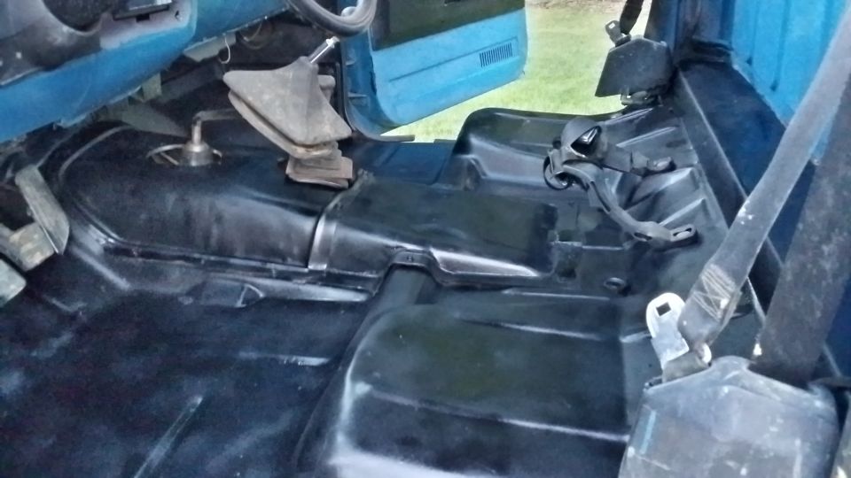 Interior floor of a truck, showing the transmission tunnel and seatbelt mounts
