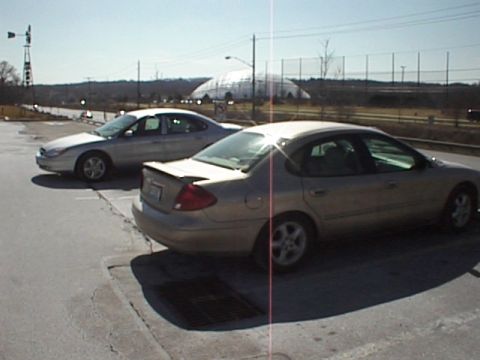 1999 Ford Taurus - A gold 1999 Ford Taurus is parked in a lot next to a silver sedan, with a domed building in the background.