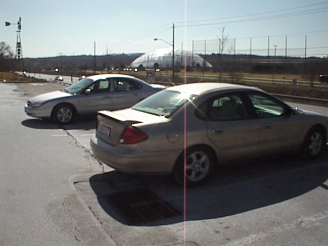 Gold 1999 Ford Taurus rear 3/4 view, parked next to a silver sedan