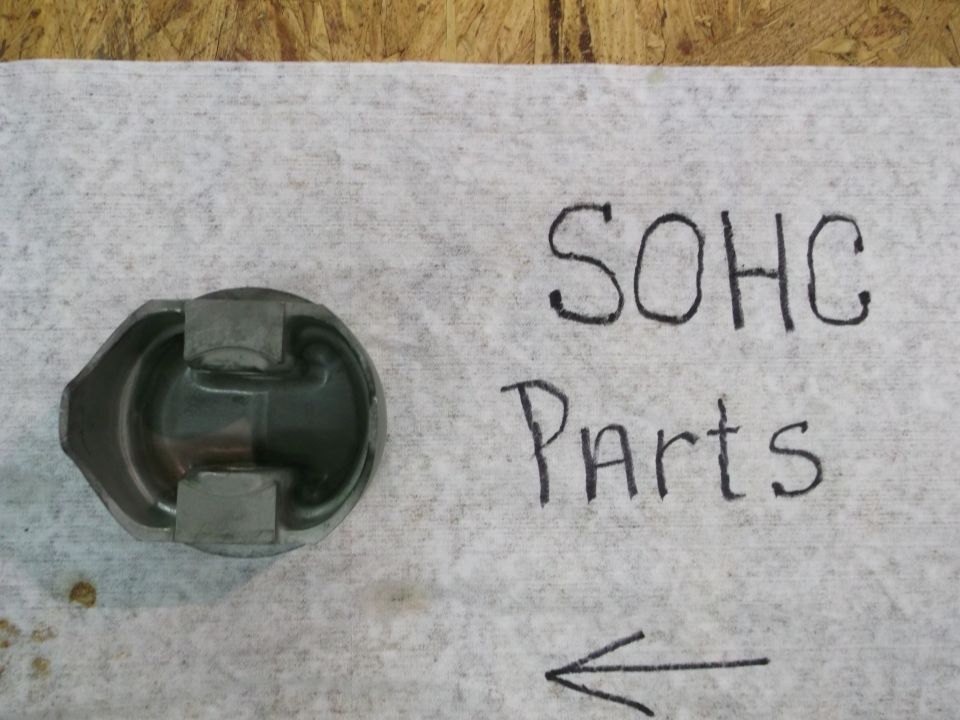 Engine piston on a white cloth with 'SOHC Parts' written next to it
