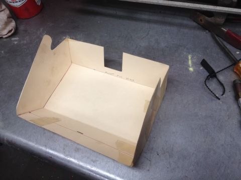1968 Mercury Cougar - A cardboard box with handwritten notes and tape sits on a workbench, possibly a part or template.