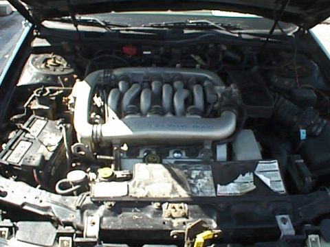 1999 Ford Taurus - The engine bay of a vehicle is shown with the hood open, revealing the V6 engine and surrounding components.