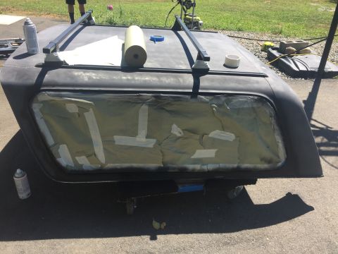 1979 Ford Bronco - A Ford Bronco hardtop is prepared for painting, with masking tape covering the rear window and spray cans on the ground.