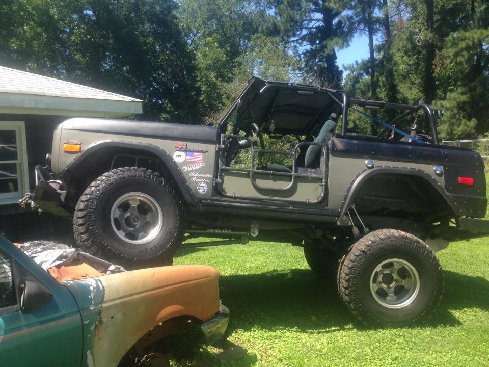 Lifted early Ford Bronco with tan and black two-tone body on grass
