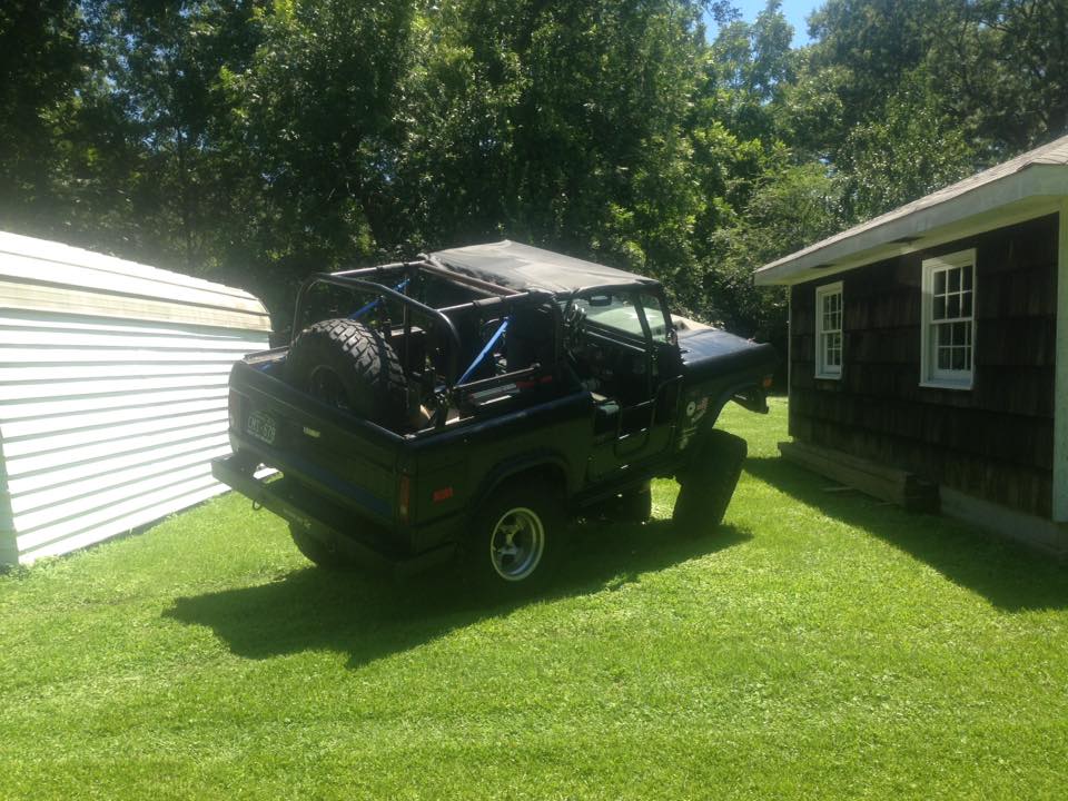 Black 1972 Ford Bronco with roll cage and spare tire in yard